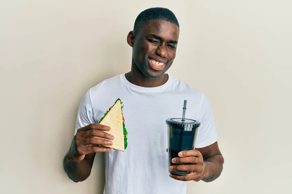 Νεαρός Αφροαμερικάνος Που Τρώει Σάντουιτς Και Πίνει Σόδα Κοιτώντας Την — Φωτογραφία Αρχείου