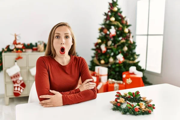 Kavkazská Mladá Blondýnka Sedící Stole Vánočního Stromku Vyděšená Šokovaná Překvapeným — Stock fotografie