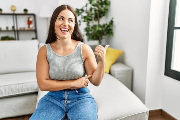 Jovem Morena Sentada Sofá Casa Sorrindo Com Rosto Feliz Olhando — Fotografia de Stock