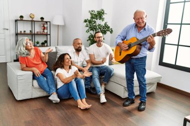 Bir grup orta yaşlı arkadaş evdeki kanepede oturup klasik gitar çalıyorlar..