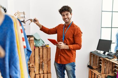 Elbise mağazasında çalışan dokunmatik ped kullanan, mutlu gülümseyen bir İspanyol esnaf..