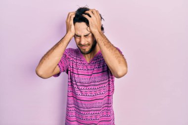 Yakışıklı, pembe tişört giyen, baş ağrısı çeken çaresiz ve stresli bir İspanyol. Çünkü acı ve migren ağrısı var. Eller başının üstünde.. 