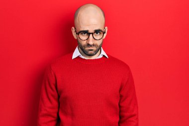 Sıradan kıyafetler giyen, gözlüklü, kuşkucu ve gergin genç kel bir adam sorun yüzünden üzgün. negatif kişi. 