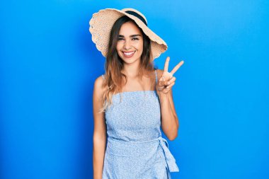 Genç İspanyol kız yaz şapkası takıyor ve iki numarayı göstererek gülümsüyor. Kendinden emin ve mutlu.. 