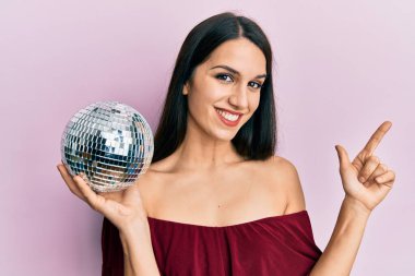 Parlak disko topunu tutan genç İspanyol kadın gülümsüyor. 