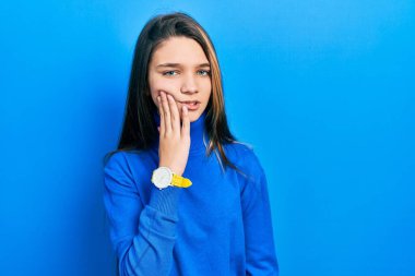 Balıkçı yaka kazak giyen genç esmer kız diş ağrısı ya da diş hastalığından dolayı acı dolu bir ifadeyle ağıza dokunuyor. dişçi 