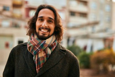 Genç İspanyol adam gülümseyerek şehirde mutlu mesut dikiliyor..