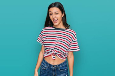 Gündelik kıyafetler giyen genç İspanyol kız kameraya seksi bir ifadeyle bakıyor, neşeli ve mutlu bir yüzle.. 