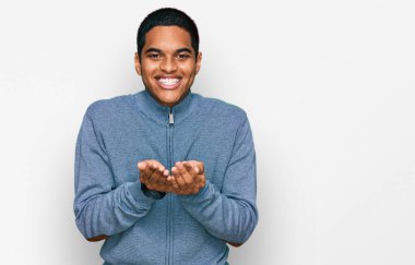 Elleri avuçlarında gülümseyen ya da el hareketi yapan sıradan bir tişört giyen genç, yakışıklı İspanyol. Bekleme ve koruma 