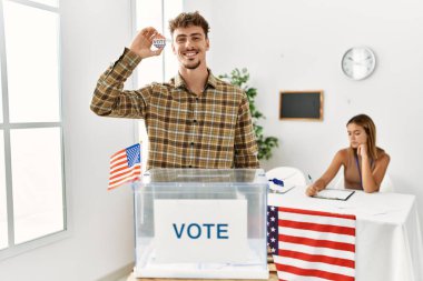 Seçmen kolejinde oy sandığının yanında rozeti olan genç Amerikalı seçmen..
