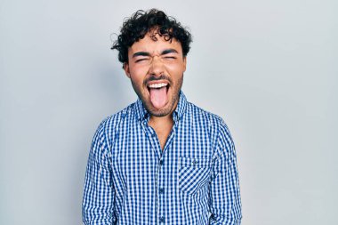 Günlük kıyafetler giyen genç İspanyol adam komik bir ifadeyle dilini dışarı çıkartıyor. duygu kavramı. 