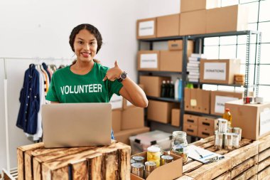 Güzel İspanyol kadın gönüllü tişört giyiyor. Dizüstü bilgisayarla çalışıyor. Gülümsüyor. 