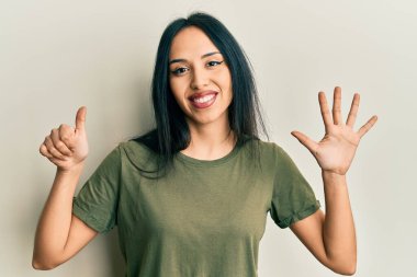 Gündelik tişört giyen genç İspanyol kız altı numarayı gösterip işaret ederken kendinden emin ve mutlu bir şekilde gülümsüyor.. 