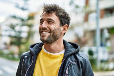 Yakışıklı, sakallı, açık havada mutlu gülümseyen bir İspanyol.