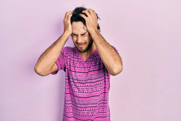 痛みや片頭痛のために必死に頭痛やストレスに苦しんでカジュアルなピンクのTシャツを着てハンサムなヒスパニック系の男 手を頭に — ストック写真
