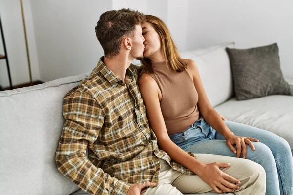 Young Hispanic Couple Kissing Hugging Sitting Sofa Home — Fotografia de Stock