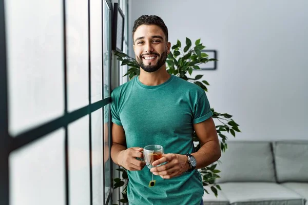 Mladý Arabský Muž Usměvavý Sebevědomý Pít Čaj Doma — Stock fotografie