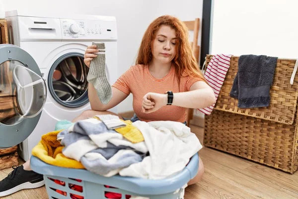 若いです赤毛女性置く汚い洗濯機にチェック時間上の手首腕時計 リラックスして自信 — ストック写真