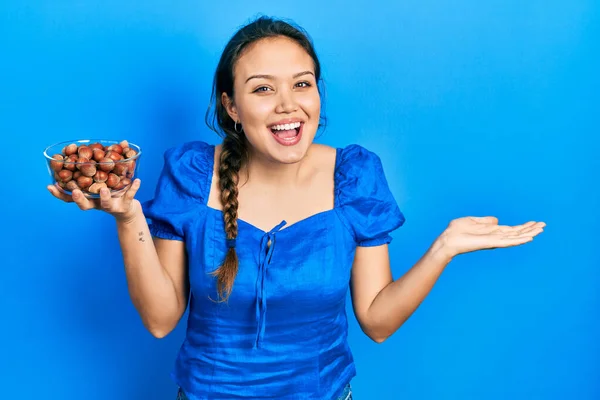 Menina Hispânica Jovem Segurando Tigela Castanhas Comemorando Realização Com Sorriso — Fotografia de Stock