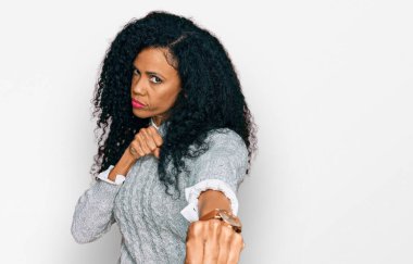 Orta yaşlı Afro-Amerikalı kadın gündelik giysiler giyiyor dövüşmek için yumruk atıyor, agresif ve öfkeli saldırı, tehdit ve şiddet 