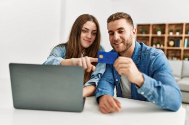 Genç beyaz çift evde dizüstü bilgisayar ve kredi kartı kullanıyor..