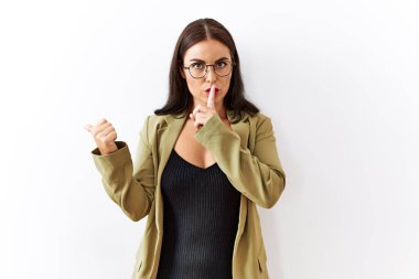 Genç esmer kadın izole edilmiş arka planda dikiliyor ve parmakları yana doğru uzanmış sessiz olmak istiyor. sessizlik ve gizli konsept. 