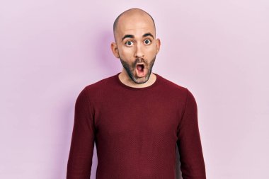 Gündelik kıyafetler giyen genç kel bir adam, korkmuş ve şok olmuş bir ifadeyle, korkuyla ve heyecanlı yüzüyle. 