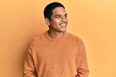 Sıradan bir kazak giyen, yüzünde gülümseme, doğal bir ifade olan genç, yakışıklı İspanyol bir adam. Kendinden emin gülen. 