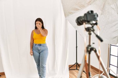 Fotoğrafçılık stüdyosunda model olarak poz veren genç, güzel İspanyol bir kadın. Burnu ve gözleri ovuşturmaktan yorulmuş, yorgunluk ve baş ağrısı hissediyordu. Stres ve hüsran kavramı. 