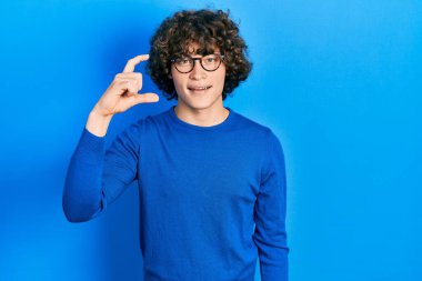 Yakışıklı, sıradan kıyafetler ve gözlük takan, gülümseyen, kendine güvenen, el hareketi yapan, parmakları küçük gösteren ve kameraya bakan genç bir adam. ölçüm kavramı. 