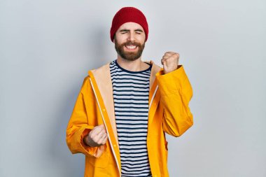 Sarı yağmurluk giyen beyaz adam kolları havada ve gözleri kapalı bir şekilde başarıyı kutluyor ve şaşırıyor. Kazanan konsept. 