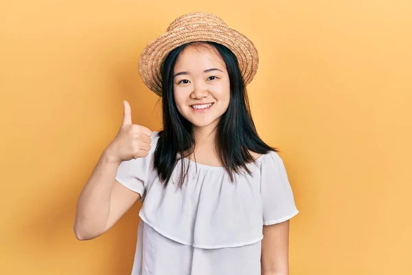 戴着夏帽的年轻中国姑娘喜形于色 大拇指高举 做得出色 签了字 — 图库照片