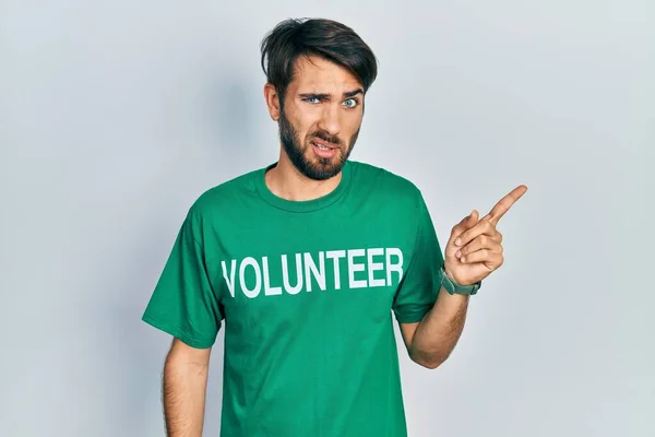 Jovem Hispânico Vestindo Camiseta Voluntária Apontando Para Lado Preocupado Nervoso — Fotografia de Stock
