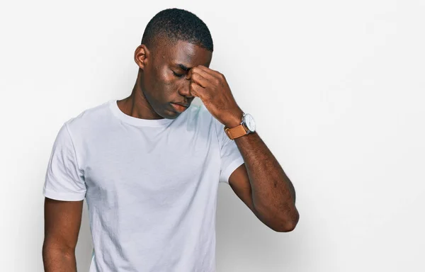 カジュアルな白いTシャツを着た若いアフリカ系アメリカ人の男性は 鼻と目をこすり疲れや頭痛を感じて疲れている ストレスとフラストレーションの概念 — ストック写真