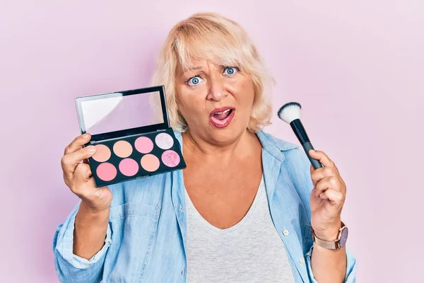 Mulher Loira Meia Idade Segurando Escova Maquiagem Blush Rosto Choque — Fotografia de Stock