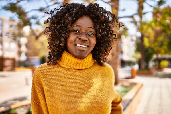 Parkta kendinden emin gülümseyen Afrikalı Amerikalı kadın.