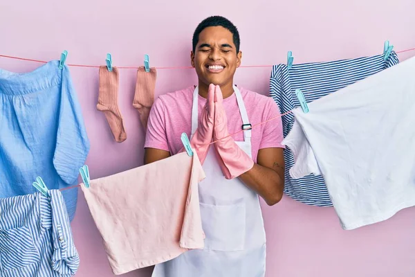 Joven Hombre Hispano Guapo Usando Delantal Más Limpio Sosteniendo Ropa —  Fotos de Stock