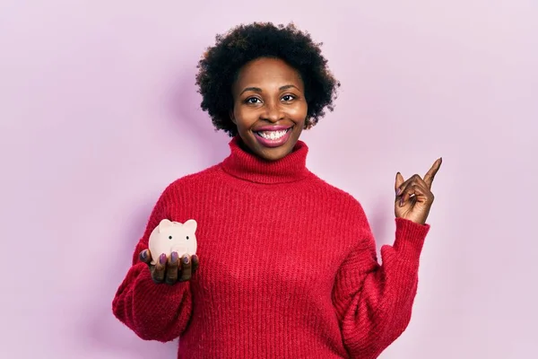 Young African American Woman Holding Piggy Bank Smiling Happy Pointing — ストック写真