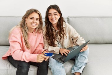 Genç çift evde dizüstü bilgisayar ve kredi kartı kullanıyor..