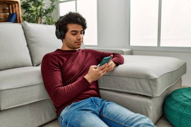 Genç İspanyol adam evde yerde oturmuş müzik dinliyor..