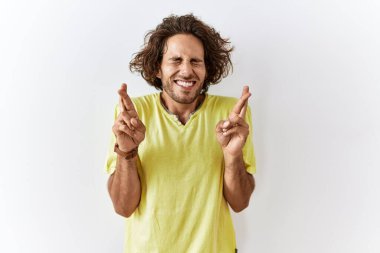 Tecrit edilmiş arka planda duran genç İspanyol adam umut ve gözlerle gülümseyerek işaret ediyor. Şans ve batıl inançlar. 