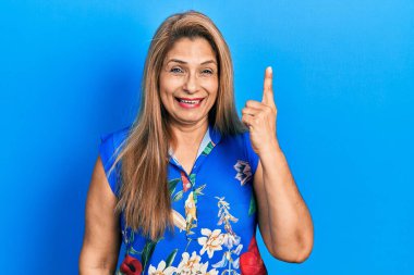 Orta yaşlı İspanyol kadın gündelik giysiler giyip başarılı bir fikri işaret ediyor. Heyecanlı ve mutlu. Bir numara.. 