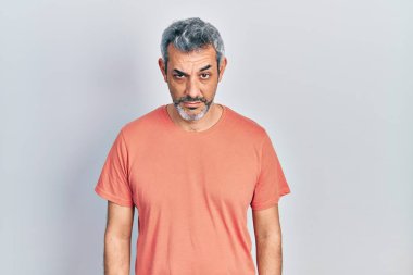 Gri saçlı, sıradan tişörtlü, kuşkucu ve gergin, sorunlu, orta yaşlı yakışıklı bir adam. negatif kişi. 