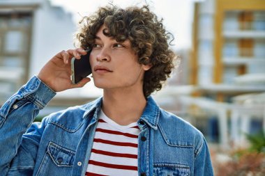 Genç İspanyol adam şehirde telefonla konuşuyor.