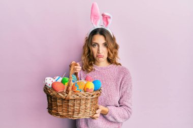 Paskalya tavşanı kulakları takan beyaz bir kadın. Renkli yumurta taşıyor. Depresyonda ve üzüntüden ağlıyor. hüzünlü ifade. 