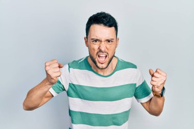 Öfkeli ve kızgın giyinmiş genç İspanyol adam öfkeyle bağırırken kızgın ve öfkeli yumruklar sallıyor. öfke ve agresif konsept. 