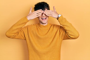 Yakışıklı hippi genç adam gündelik sarı süveter giyiyor. Gözleri kapatıyordu. Neşeli ve komik gülümsüyordu. kör kavram. 