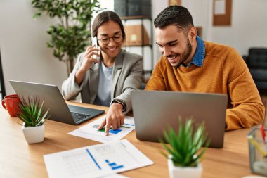 İki iş adamı akıllı telefondan konuşuyor ve ofiste dizüstü bilgisayar kullanıyorlar..