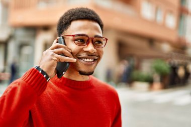 Yakışıklı Afro-Amerikan adam dışarıda telefonda konuşuyor.