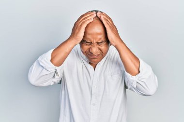 Orta yaşlı, gündelik kıyafetler giyen, baş ağrısı çeken çaresiz ve stresli bir adam. Çünkü acı ve migren ağrısı var. Eller başının üstünde.. 